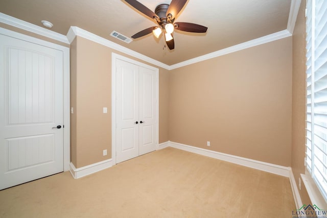 unfurnished bedroom featuring ceiling fan, a closet, light carpet, and ornamental molding