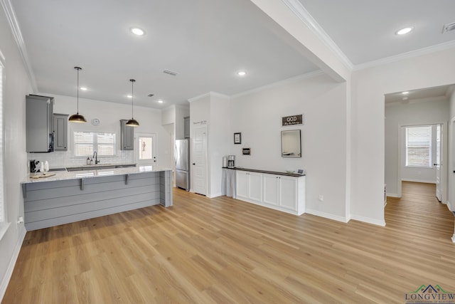 kitchen with stainless steel fridge, tasteful backsplash, a wealth of natural light, gray cabinetry, and light hardwood / wood-style floors