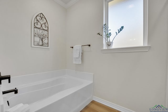 bathroom with a tub, crown molding, and hardwood / wood-style flooring