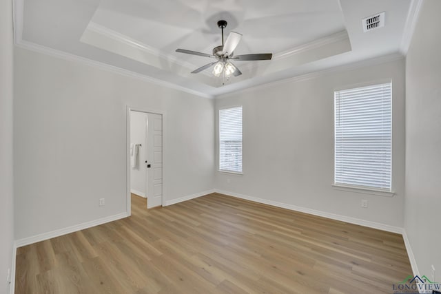 empty room with light hardwood / wood-style floors, a raised ceiling, ceiling fan, and crown molding