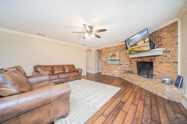 living room featuring brick wall, hardwood / wood-style floors, a brick fireplace, crown molding, and ceiling fan