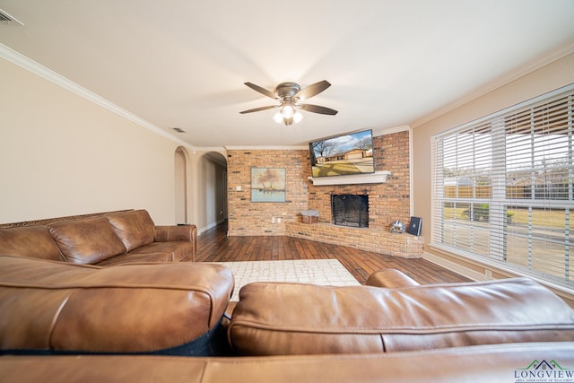 living room with ceiling fan, hardwood / wood-style floors, crown molding, and a fireplace