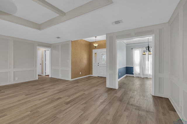 unfurnished room with a chandelier, beam ceiling, and light hardwood / wood-style floors