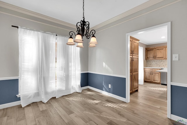 unfurnished dining area with light hardwood / wood-style floors, an inviting chandelier, and crown molding