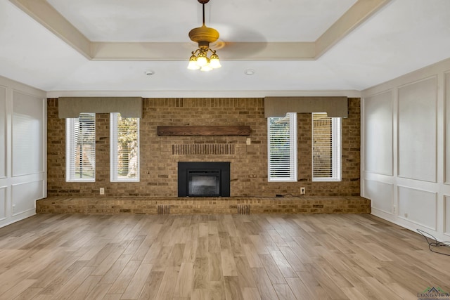 unfurnished living room with a tray ceiling, a healthy amount of sunlight, and light hardwood / wood-style floors