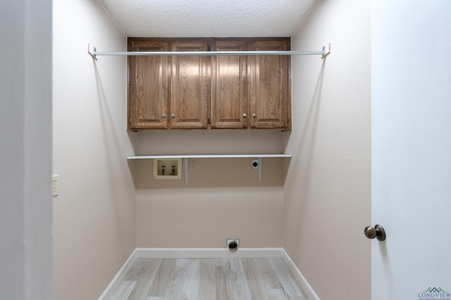 clothes washing area with cabinets, washer hookup, a textured ceiling, and electric dryer hookup