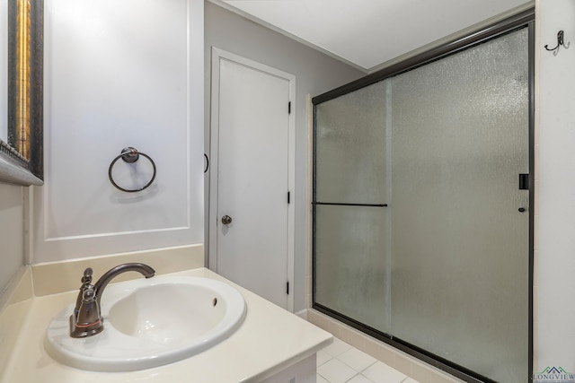 bathroom with a shower with door, vanity, and tile patterned flooring