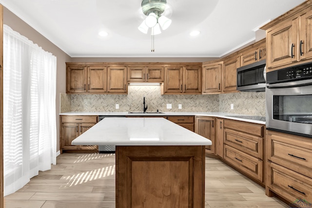 kitchen featuring decorative backsplash, appliances with stainless steel finishes, light wood-type flooring, sink, and a kitchen island