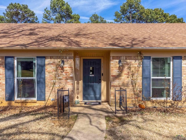 property entrance with brick siding and a shingled roof