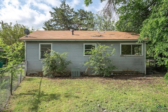 rear view of property with a yard, central AC, and fence