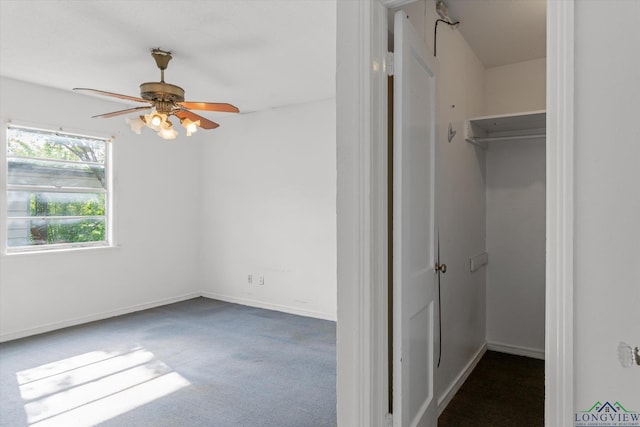 unfurnished bedroom featuring a closet, baseboards, a walk in closet, and carpet floors