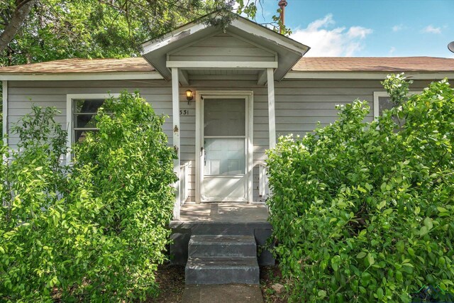 property entrance featuring roof with shingles