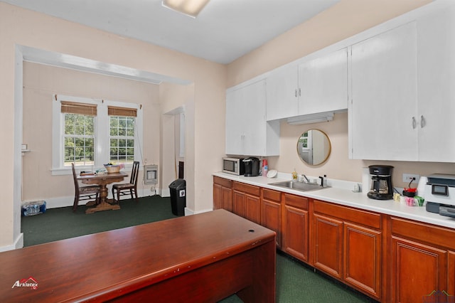 kitchen featuring heating unit, sink, and white cabinets