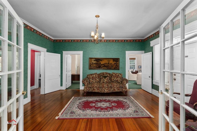 living area with french doors, dark hardwood / wood-style flooring, an inviting chandelier, and ornamental molding