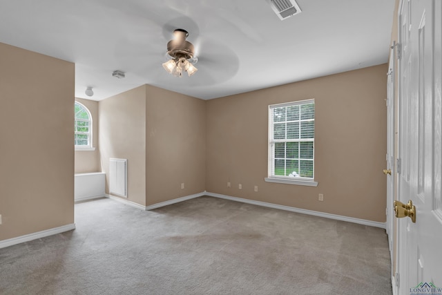 unfurnished room with ceiling fan, light colored carpet, and a wealth of natural light