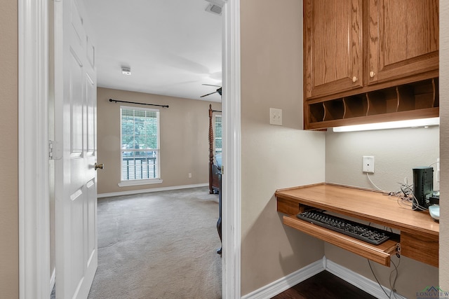 carpeted office featuring built in desk and ceiling fan