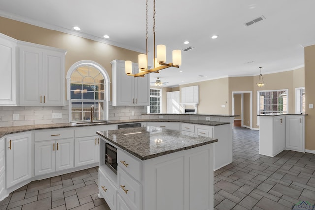 kitchen with ceiling fan, decorative backsplash, sink, and a kitchen island