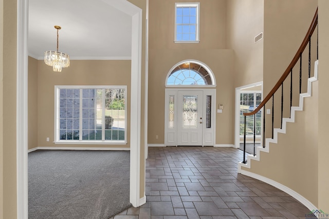 entrance foyer with an inviting chandelier, a wealth of natural light, crown molding, and a towering ceiling