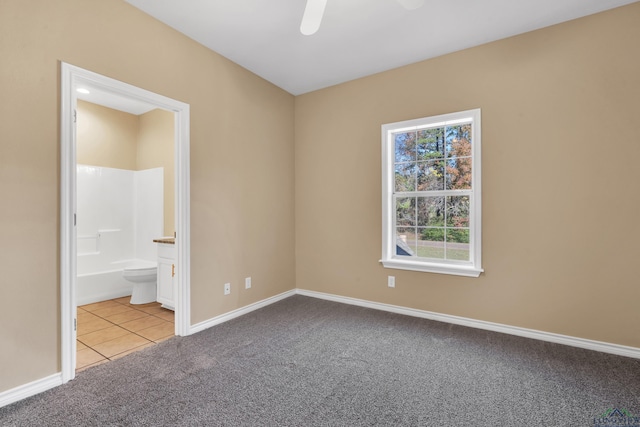 unfurnished bedroom featuring ceiling fan, light carpet, and ensuite bath