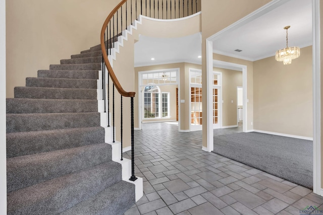 entrance foyer with ornamental molding, carpet floors, and a notable chandelier