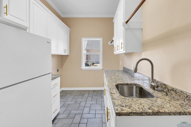 kitchen with white cabinetry, white fridge, sink, stone countertops, and crown molding