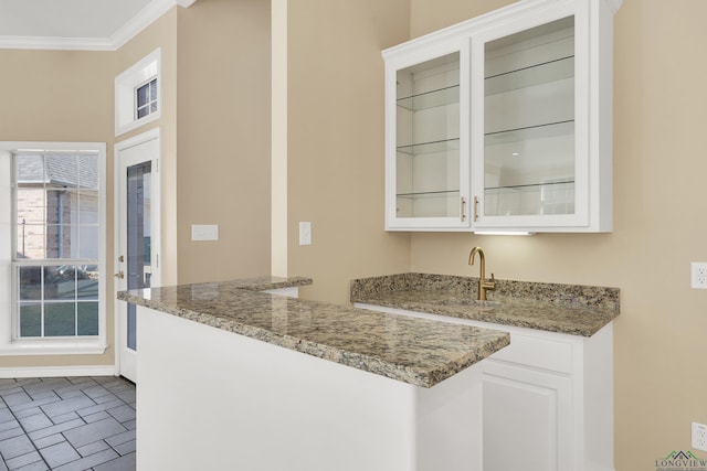 bar with crown molding, sink, light stone counters, and white cabinetry