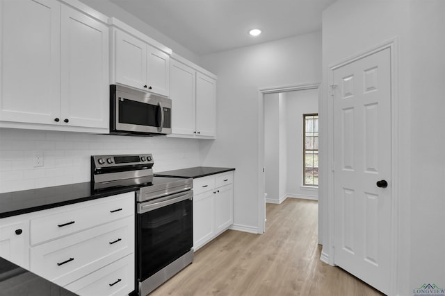 kitchen with white cabinetry, appliances with stainless steel finishes, light hardwood / wood-style floors, and backsplash