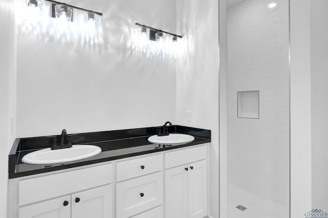 bathroom featuring tiled shower and vanity