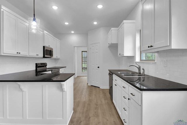 kitchen with hanging light fixtures, white cabinetry, sink, and electric range