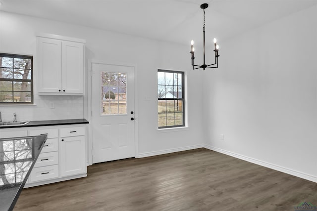 unfurnished dining area featuring dark hardwood / wood-style flooring, sink, and an inviting chandelier