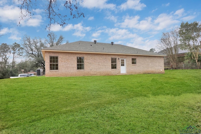 rear view of house featuring central AC unit and a lawn