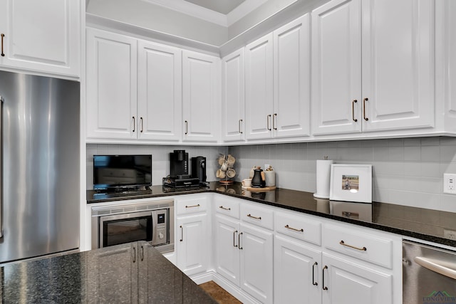 kitchen with dark stone countertops, white cabinetry, stainless steel appliances, and tasteful backsplash