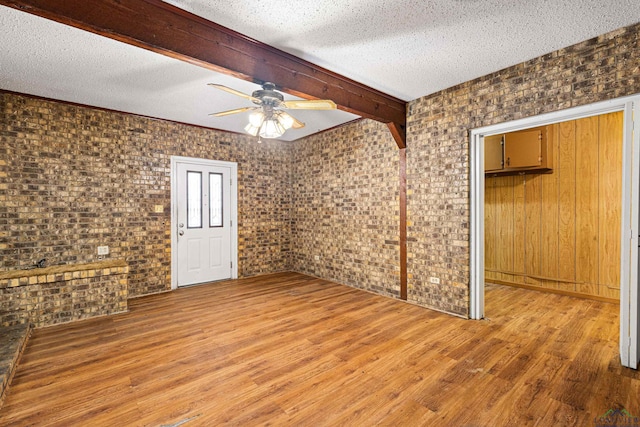 unfurnished room with hardwood / wood-style flooring, a textured ceiling, ceiling fan, and beamed ceiling