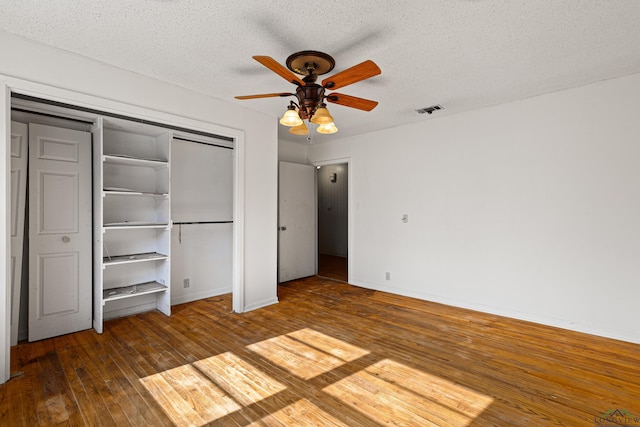 unfurnished bedroom with a textured ceiling, ceiling fan, and dark wood-type flooring