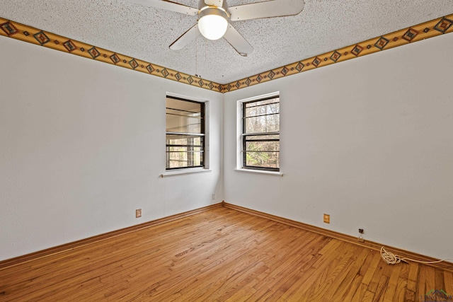 spare room featuring light wood-type flooring, ceiling fan, and a textured ceiling