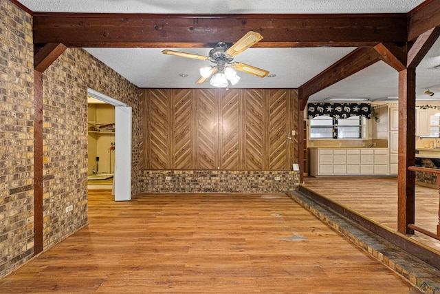 unfurnished room featuring a textured ceiling, hardwood / wood-style floors, ceiling fan, and beam ceiling