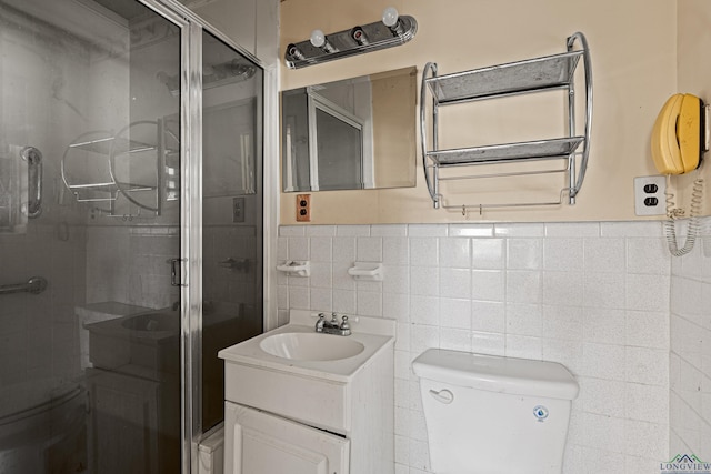 bathroom with toilet, a shower with shower door, tile walls, and vanity