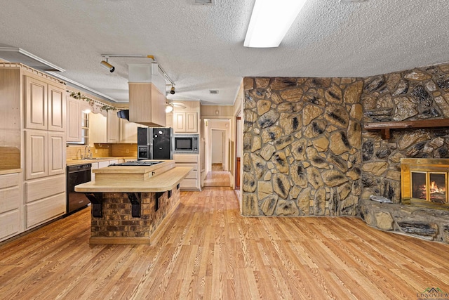 kitchen featuring black appliances, track lighting, a fireplace, and light brown cabinets