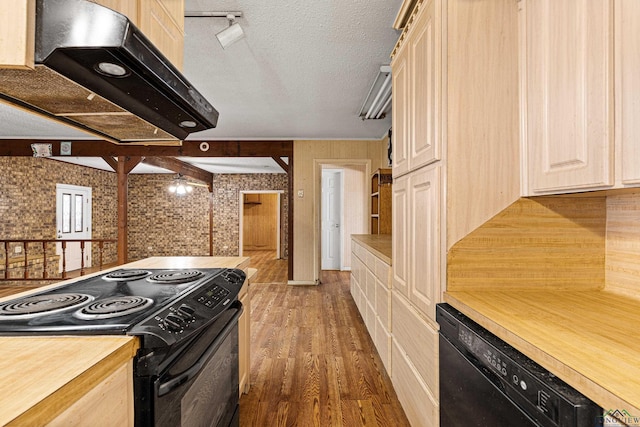 kitchen with black appliances, dark hardwood / wood-style flooring, wooden walls, light brown cabinetry, and a textured ceiling