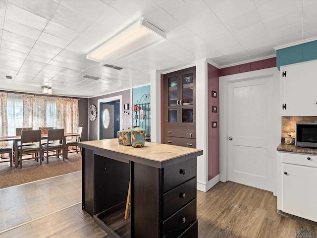 kitchen with hardwood / wood-style flooring, a center island, white cabinets, and ornamental molding