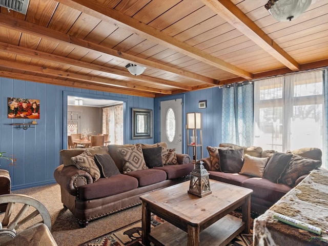 carpeted living room with beam ceiling, plenty of natural light, wooden ceiling, and wood walls