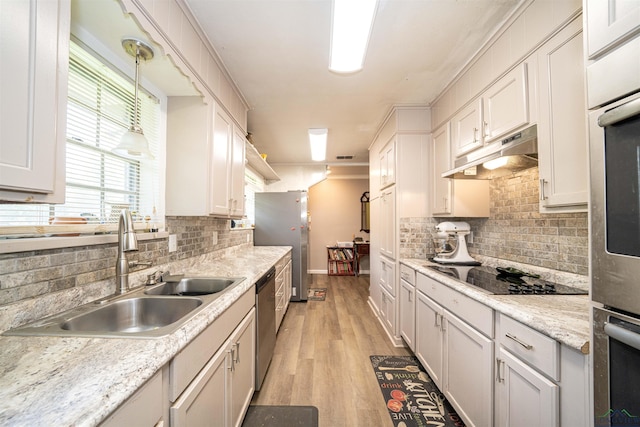 207 E Eleanor St, Gladewater, TX 75647 - kitchen featuring under cabinet range hood, appliances with stainless steel finishes, light wood-type flooring, light countertops, and decorative backsplash