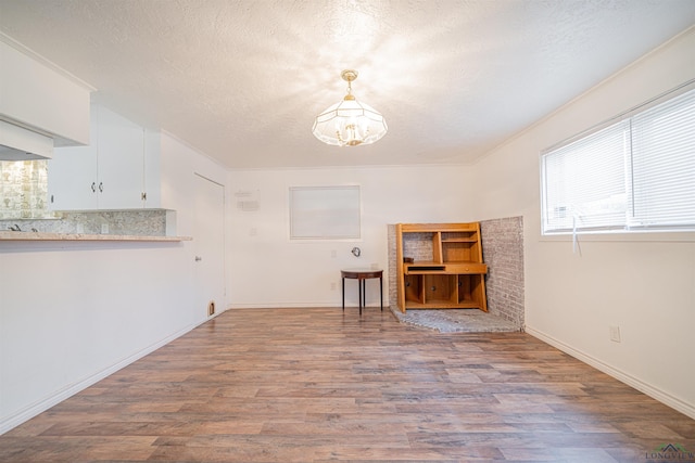 interior space with crown molding, light hardwood / wood-style flooring, a chandelier, and a textured ceiling