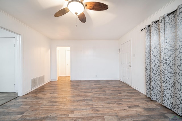 empty room with dark hardwood / wood-style floors, ceiling fan, and ornamental molding