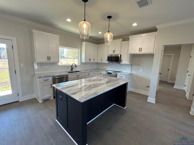 kitchen featuring decorative backsplash, white cabinetry, a center island, and appliances with stainless steel finishes