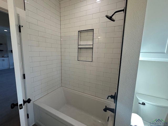 bathroom featuring tiled shower / bath combo and toilet