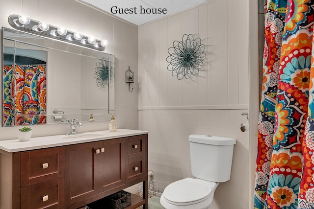 bathroom featuring toilet, a textured ceiling, curtained shower, and vanity