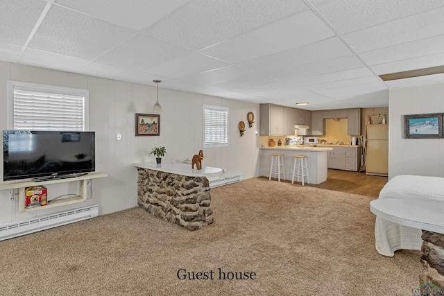 carpeted living room with a drop ceiling and a baseboard heating unit