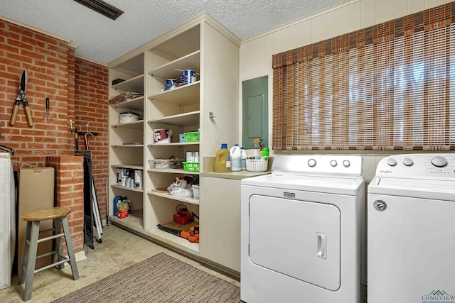 clothes washing area with washer and dryer, a textured ceiling, and electric panel