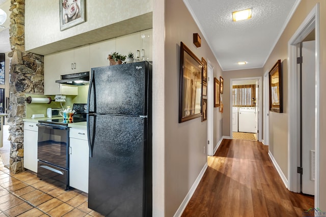 kitchen featuring black appliances, washing machine and dryer, a textured ceiling, white cabinets, and light hardwood / wood-style flooring